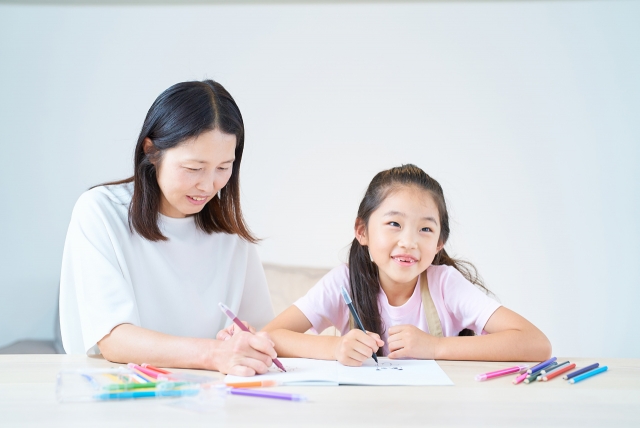 勉強を見る女性と笑顔の少女